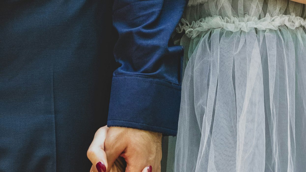 A woman holding the arm of a man with a ring on her finger.