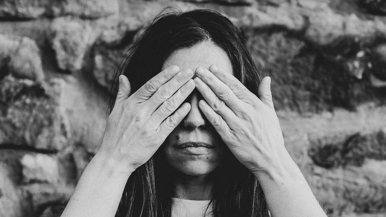 A woman in a black and white photo holds her hands over her eyes