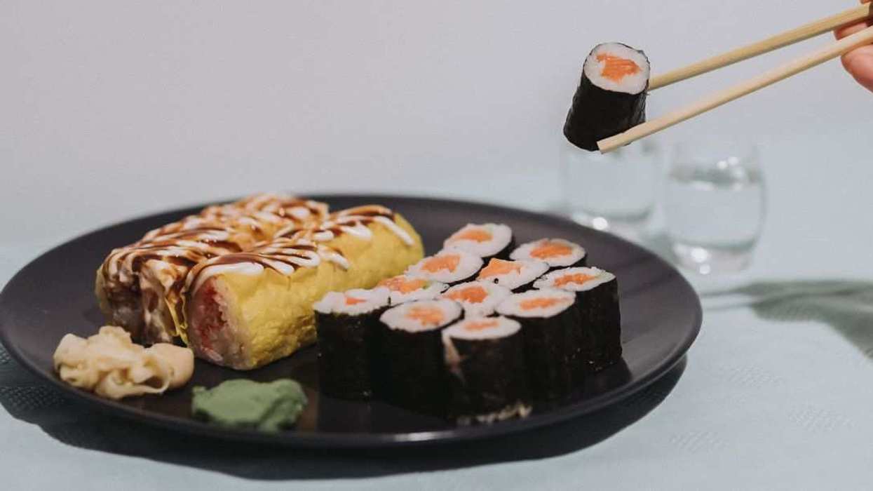 A woman is eating banana sushi rolls and salmon maki sushi rolls in Athens, Greece.