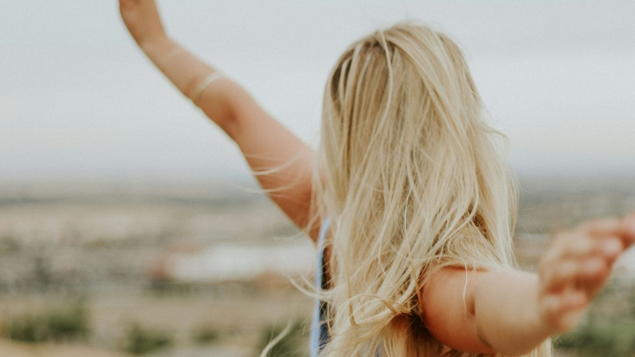 A woman outsiide holding her arms out