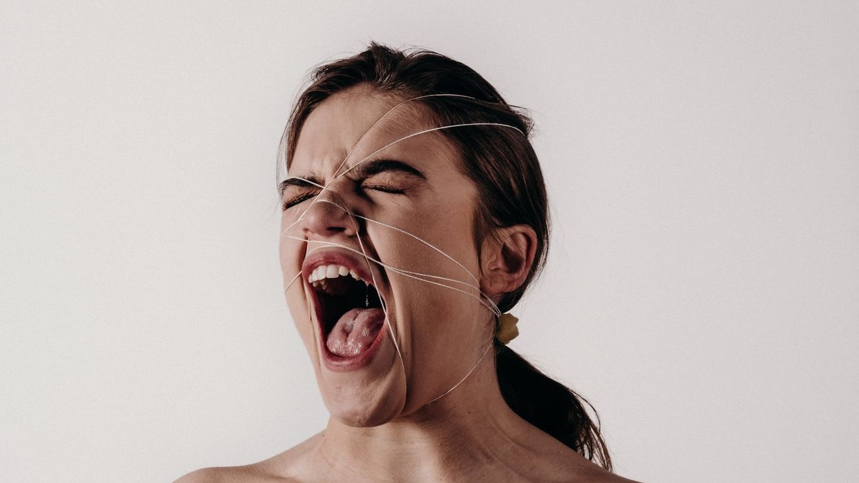 A woman yells in frustration with white wire wrapped around her head