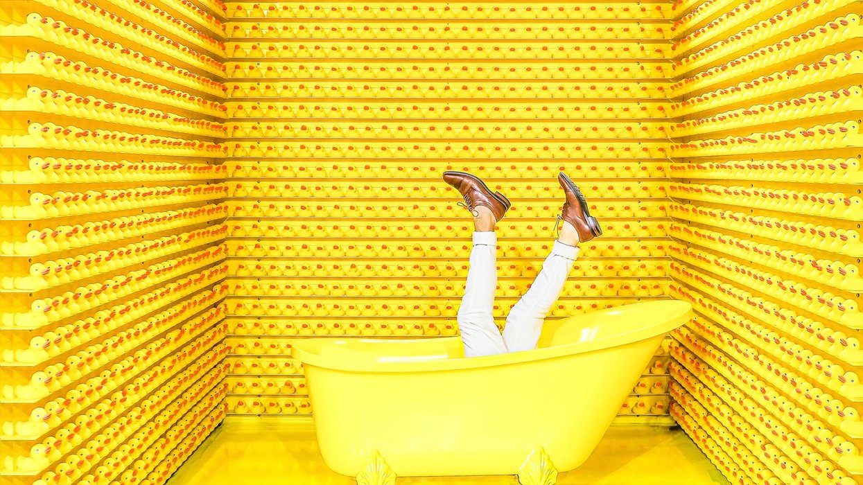 A yellow room. A yellow tub with legs pointing to sky, wearing white pants and brown shoes