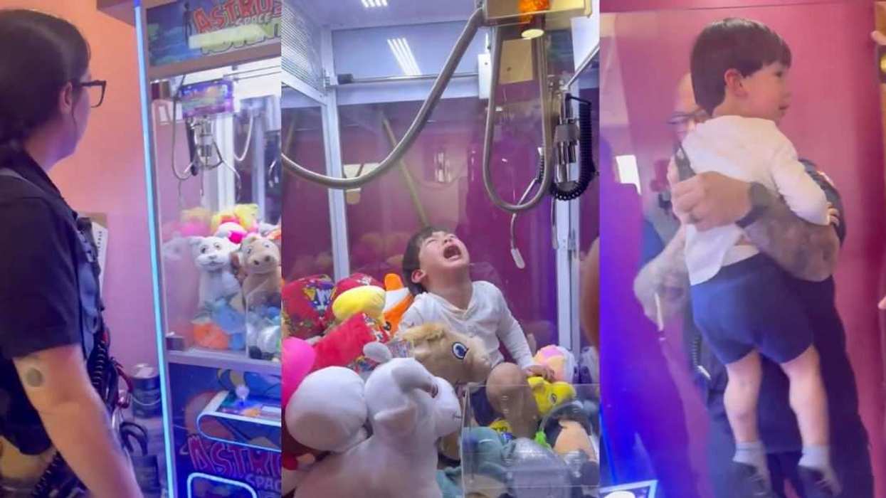 A young boy cries inside a claw machine as firefighters work to rescue him.