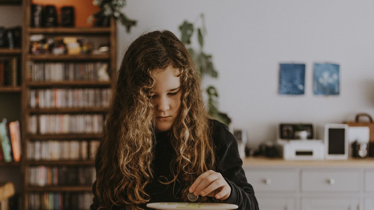 A young girl is about to put a coin into a moneybox