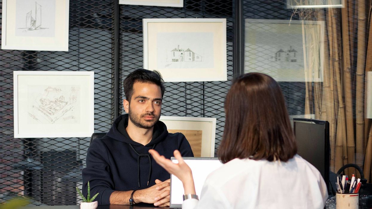 A young man looks uninterested during a job interview with a brunette woman.