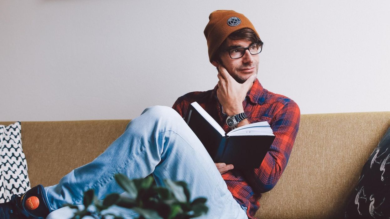 A young man sits and thinks while holding a book