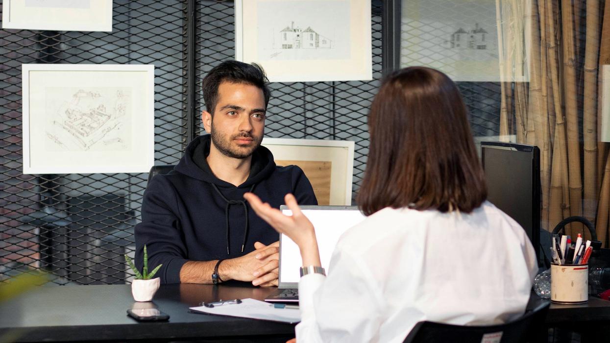 A young man sits in a job interview across from a woman we can't see, and he's seems bored.