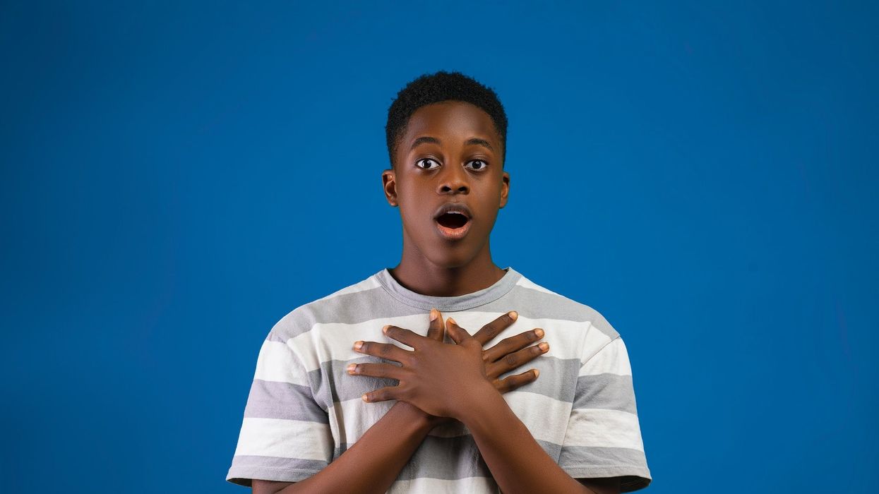 A young man stands in shock with his hands folded over his chest