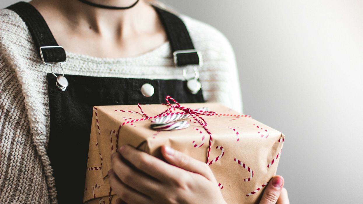A young woman clutches a wrapped Christmas gift to her chest.