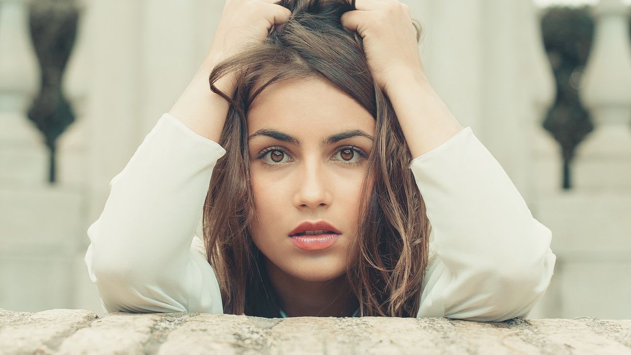 A young woman holds up her hair in frustration