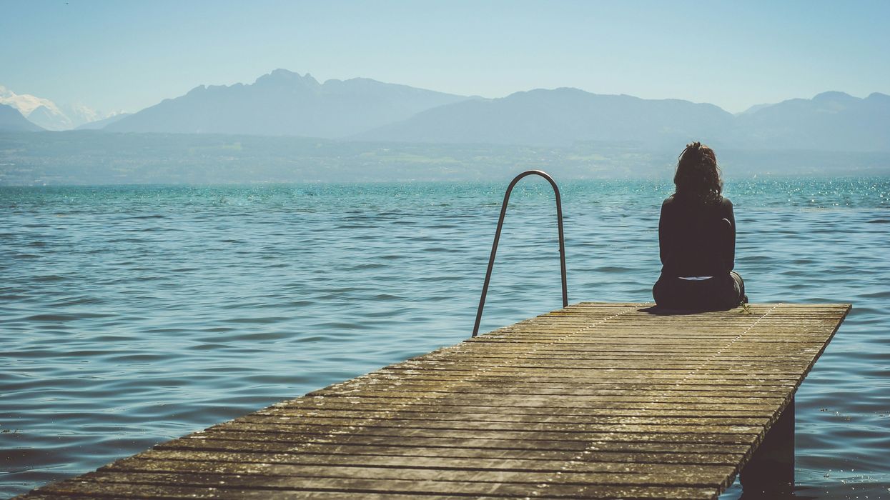 A  young woman sitting at the edge of a pier