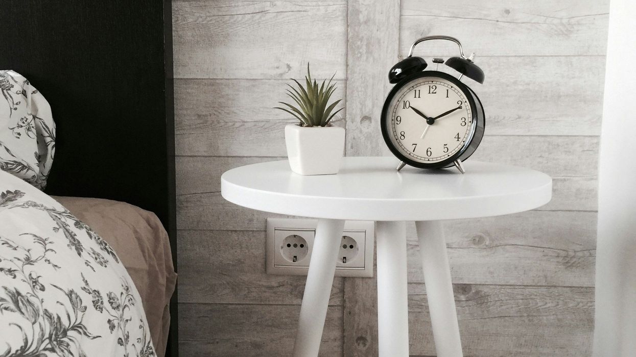 An Alarm clock sitting on a bedside table
