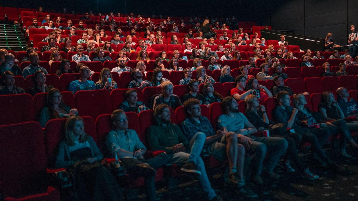 An audience sit in a theater watching a movie