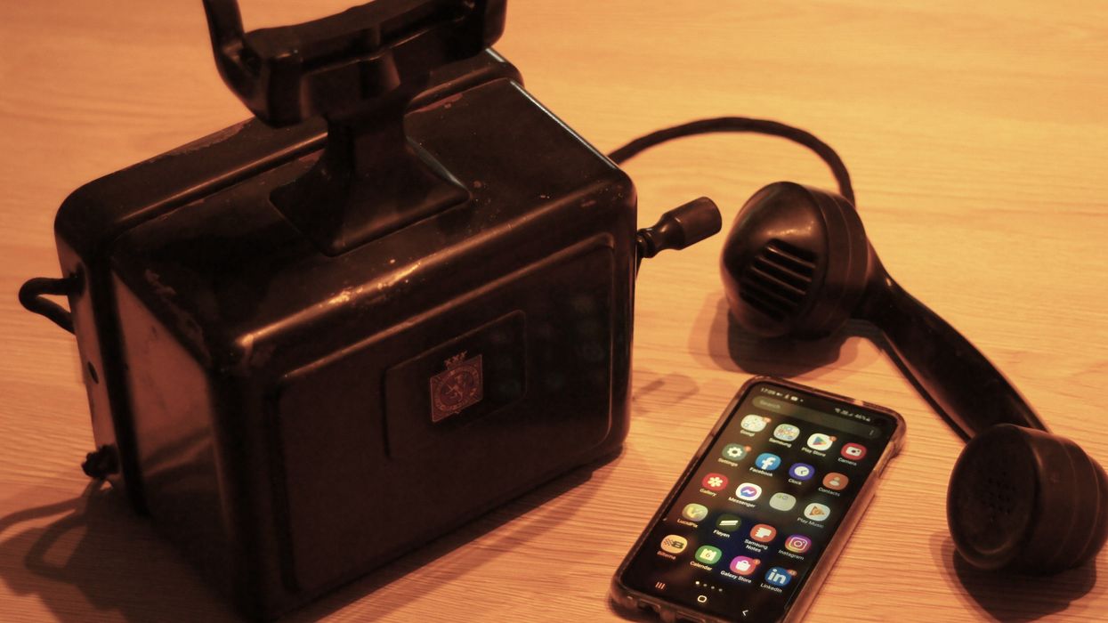 An iPhone next to an antique telephone