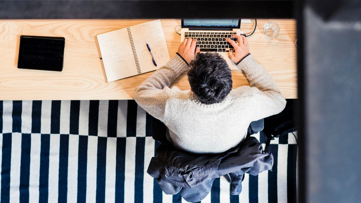 An over the head shot of a man working on his computer at his desk