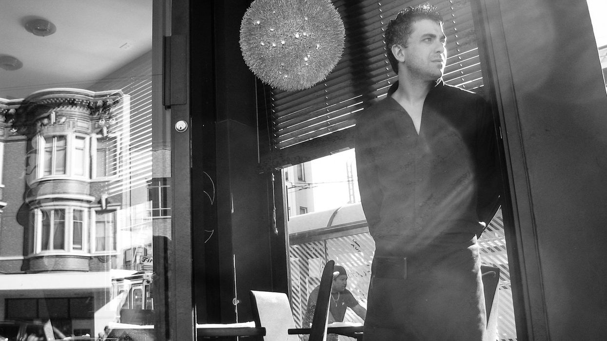 Black and white photo of a server dressed in all black peering through a window.