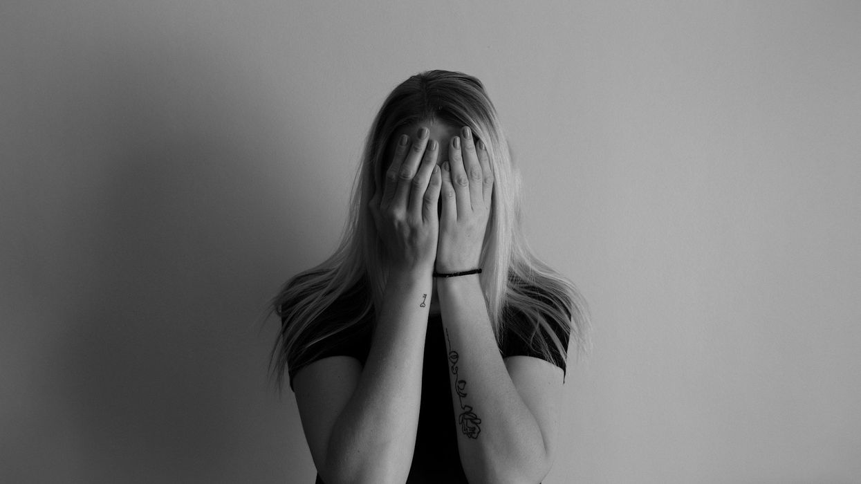 Black and white photo of a young, blonde woman holding her face in her hands.