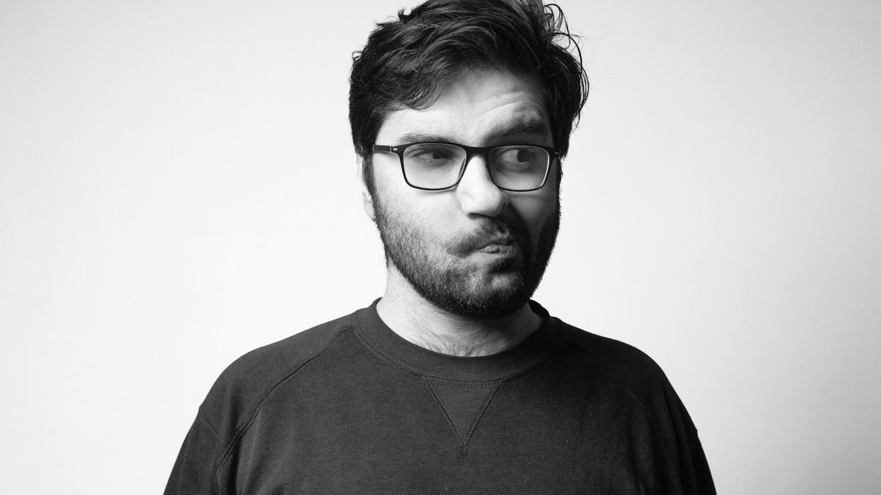 Black and white photo of a young man with glasses. He moves his mouth to the side making an odd pose.