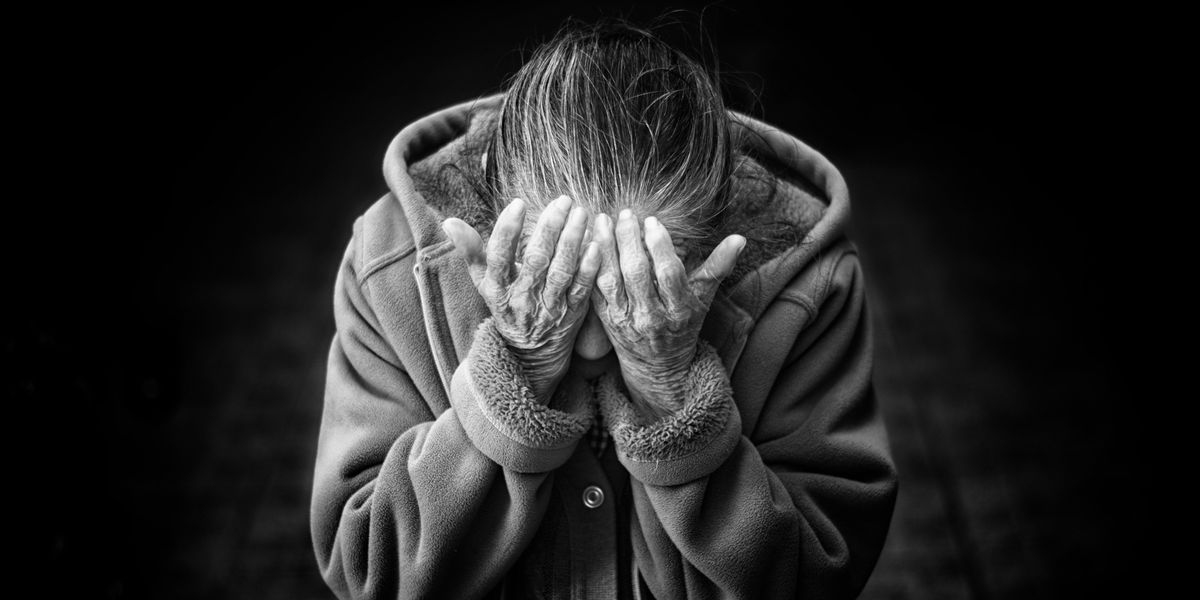 Black and white photo of an elderly person holding their face in their hands