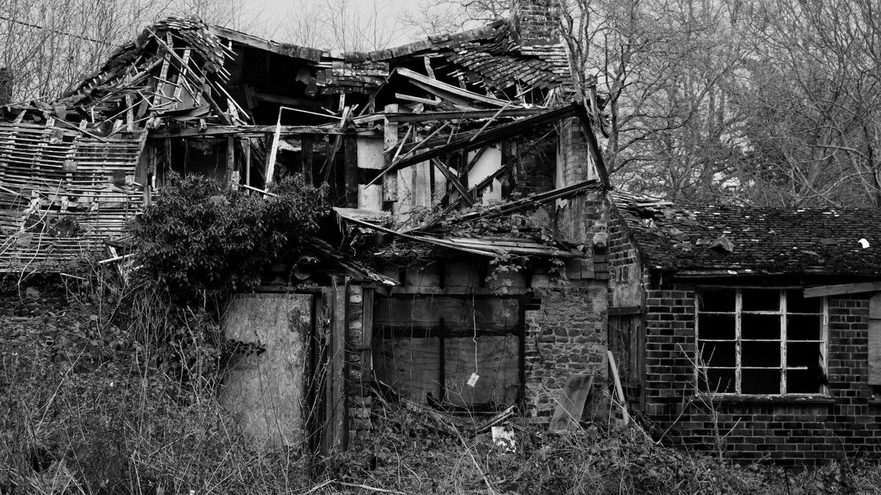 Black and white photo of an old dilapidated house, the roof is caving in.