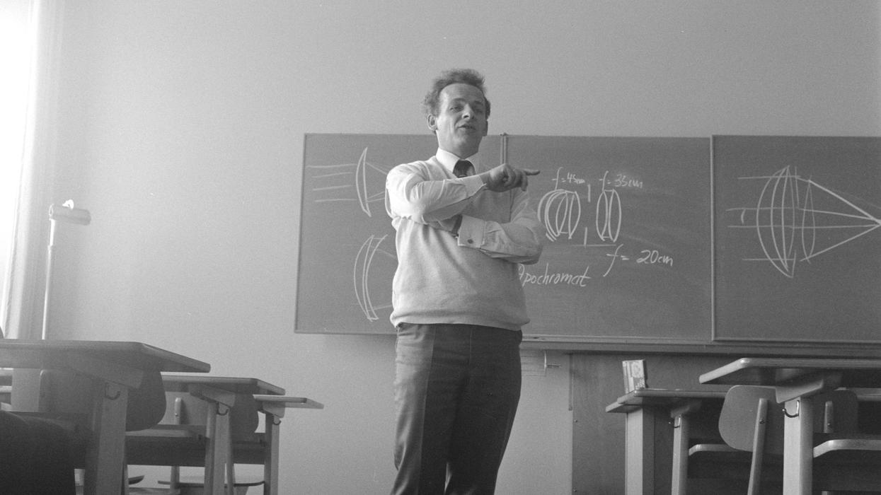 Black and white photo of teacher standing at front of classroom