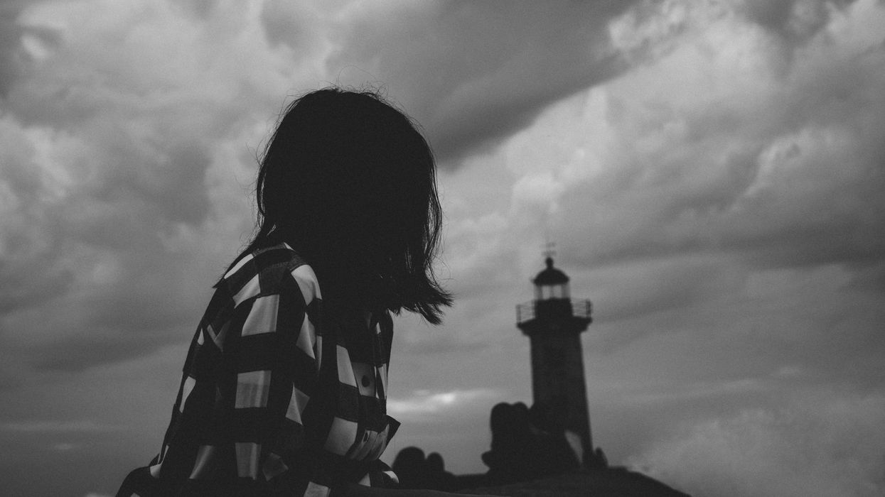 black and white photograph of a woman staring at a lighthouse