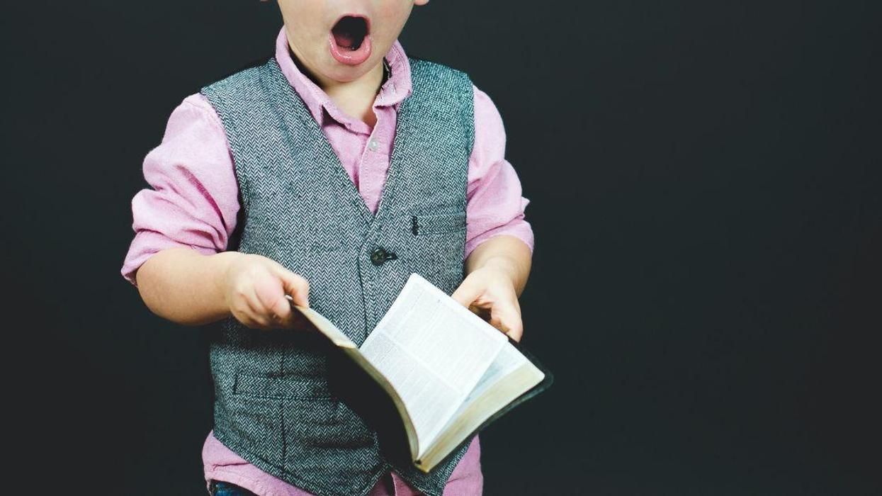 Boy holding a book looking shocked