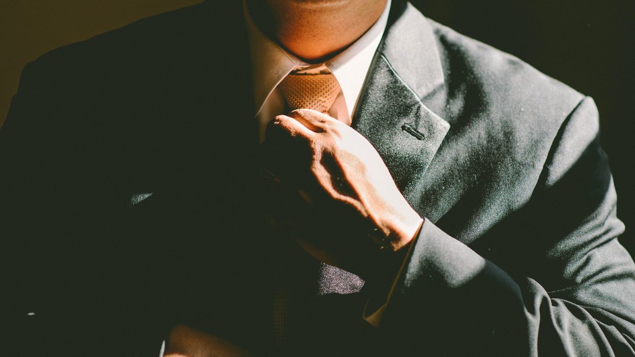 businessman straightening tie in dim lighting