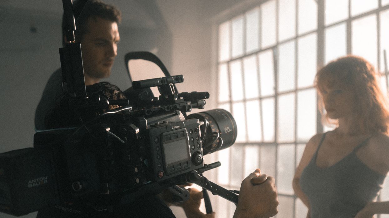 Cameraman filming woman in front of window