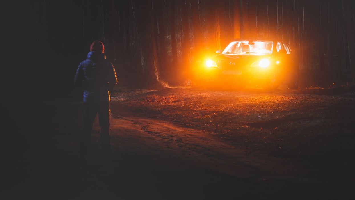 car headlights illuminating man in woods