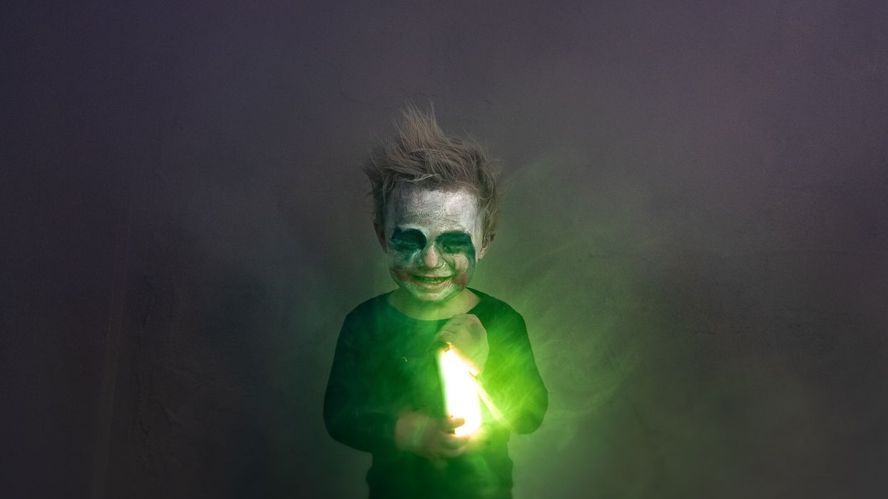 Child disguised as DC's Joker while holding an evil-looking green light