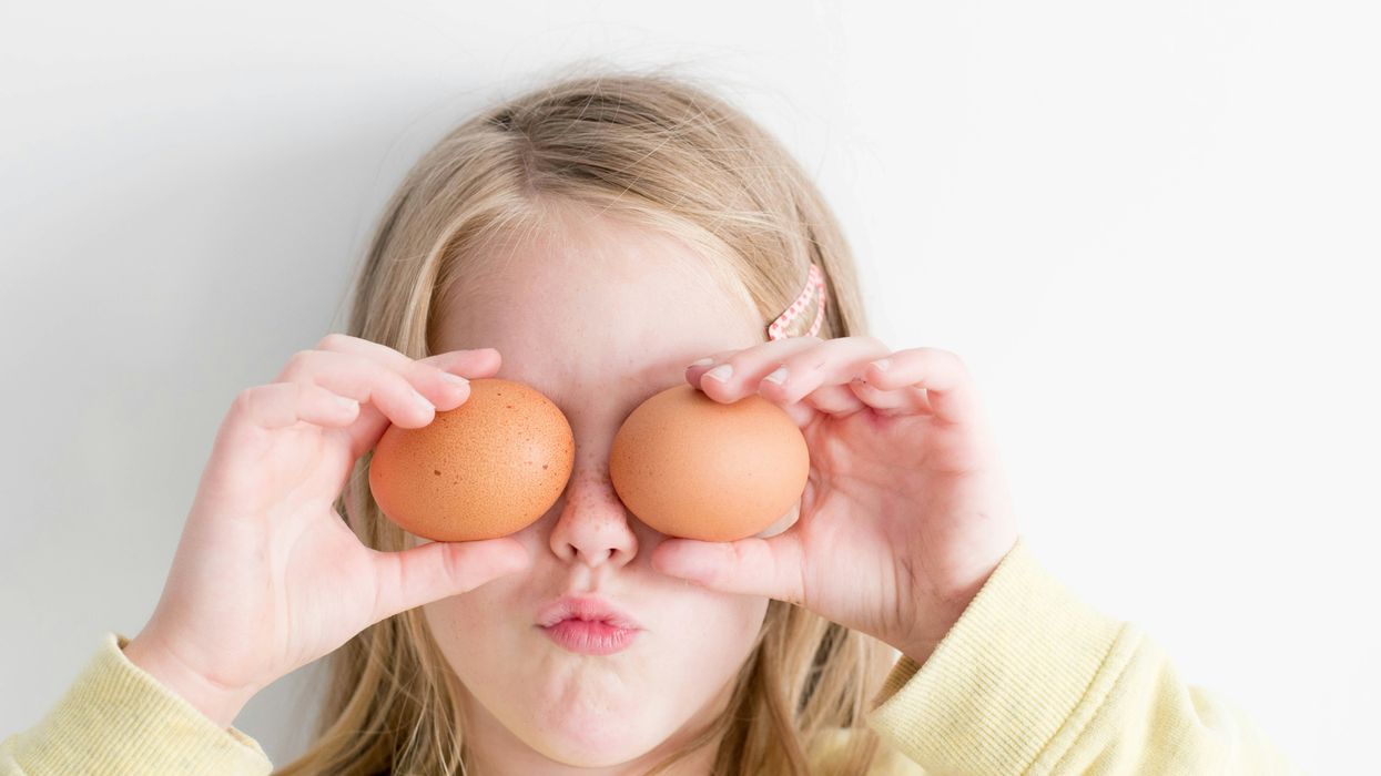 Child holding up hard boiled eggs to cover their eyes