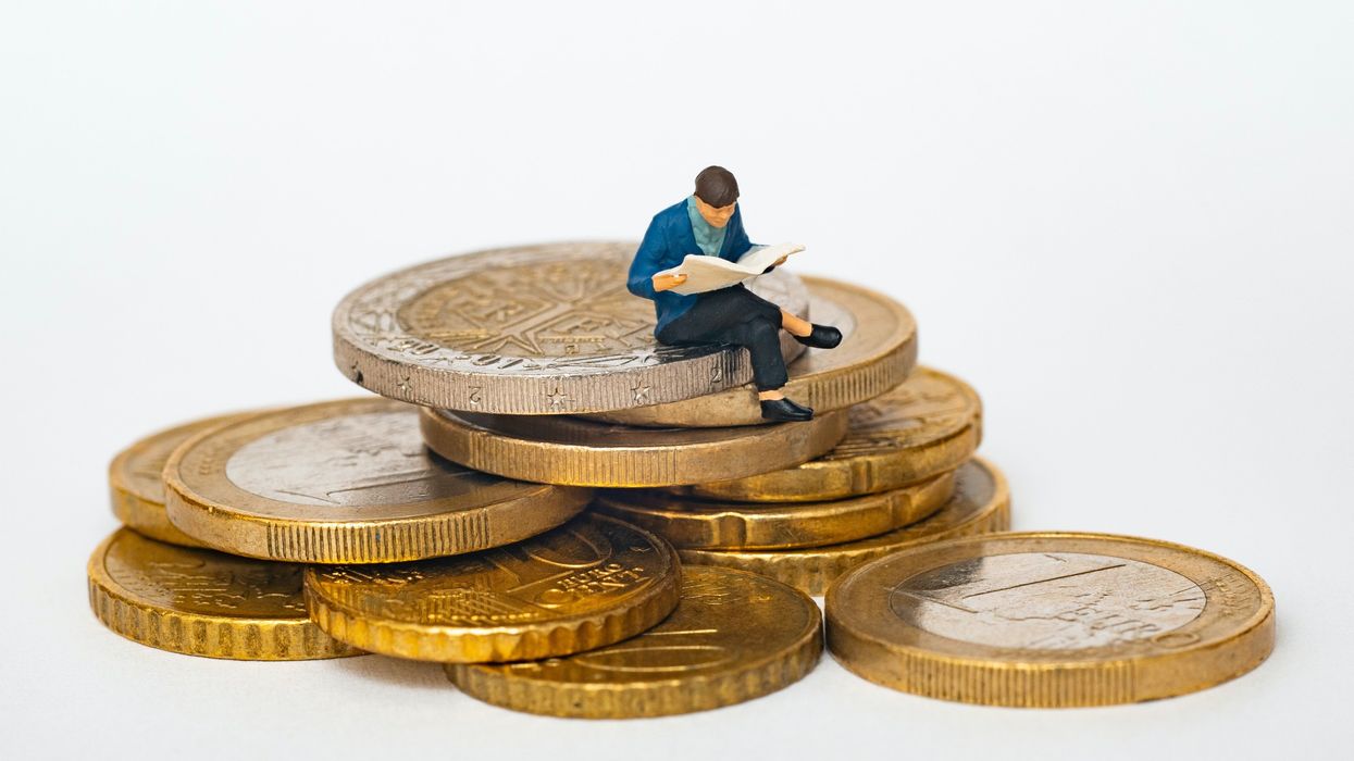 Clay doll sitting on a stack of gold coins