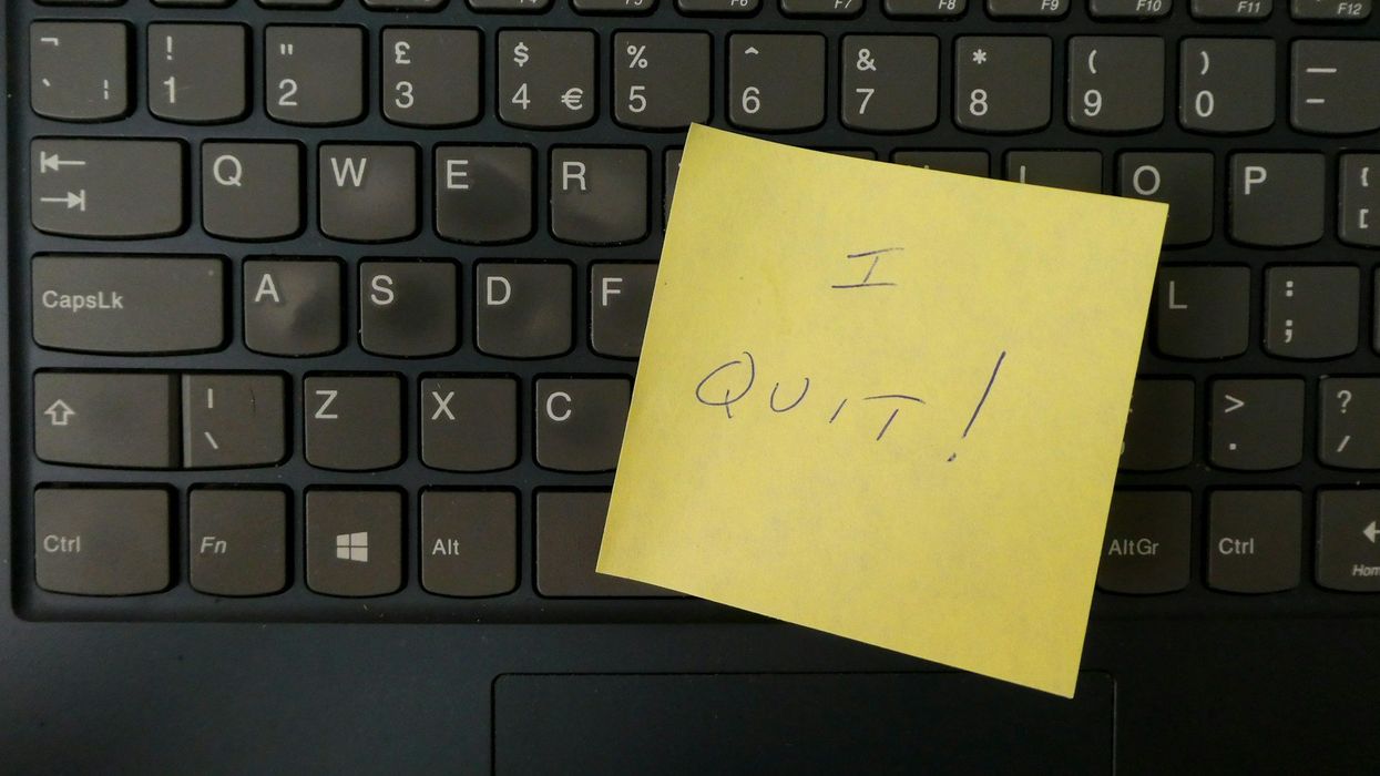 Close-up of a black computer keyboard. A yellow post-it sign is stuck to it, it says "I QUIT!"