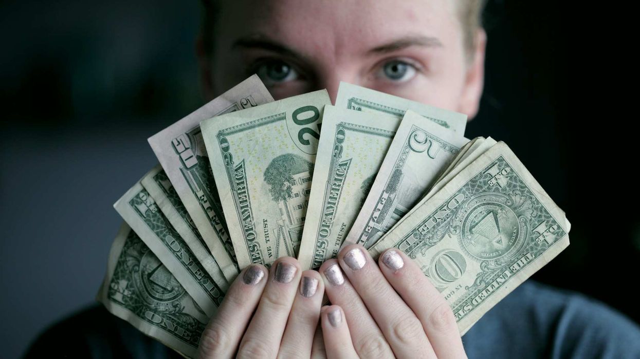 Close-up of a person holding up fanned out bills of money.