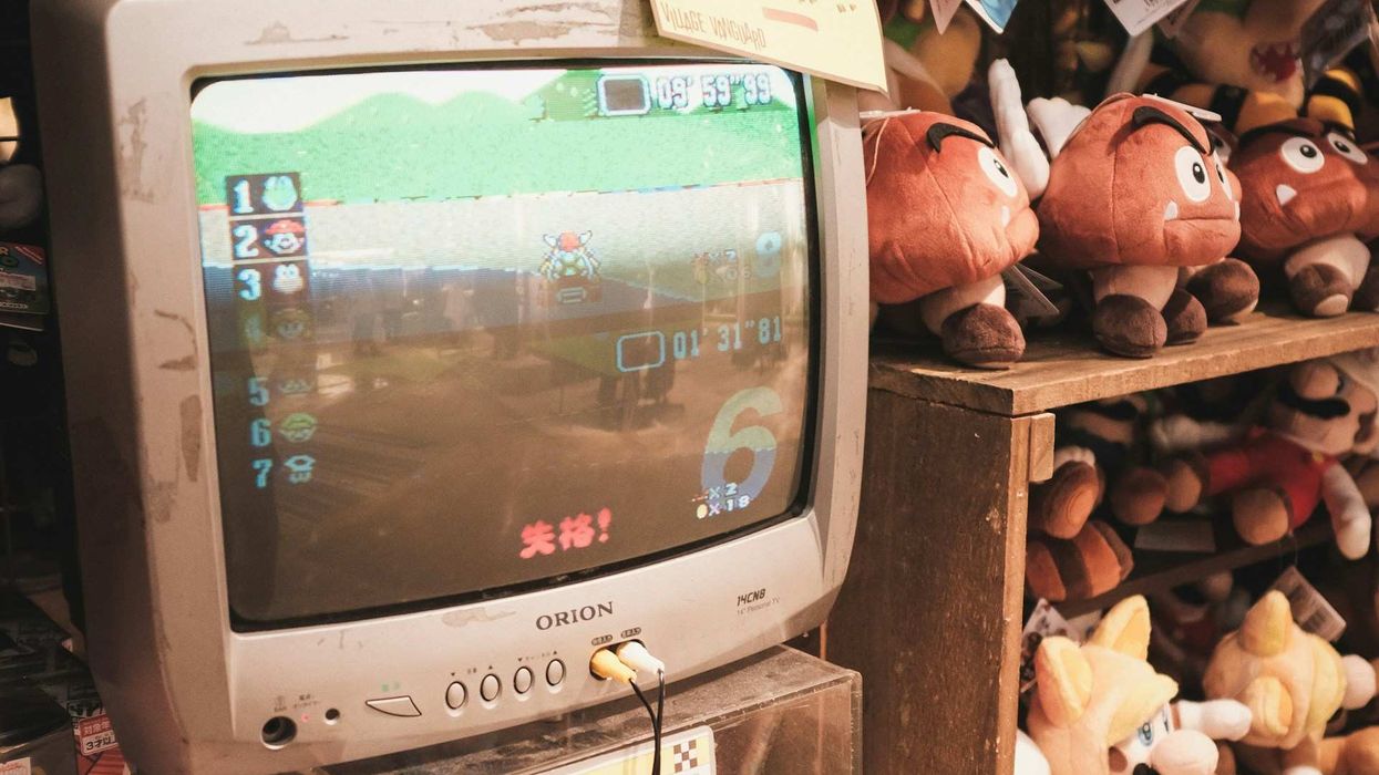 Close-up shot of a small, old school tv airing a video game; outdated, stuffed animals and toys surround the tv.