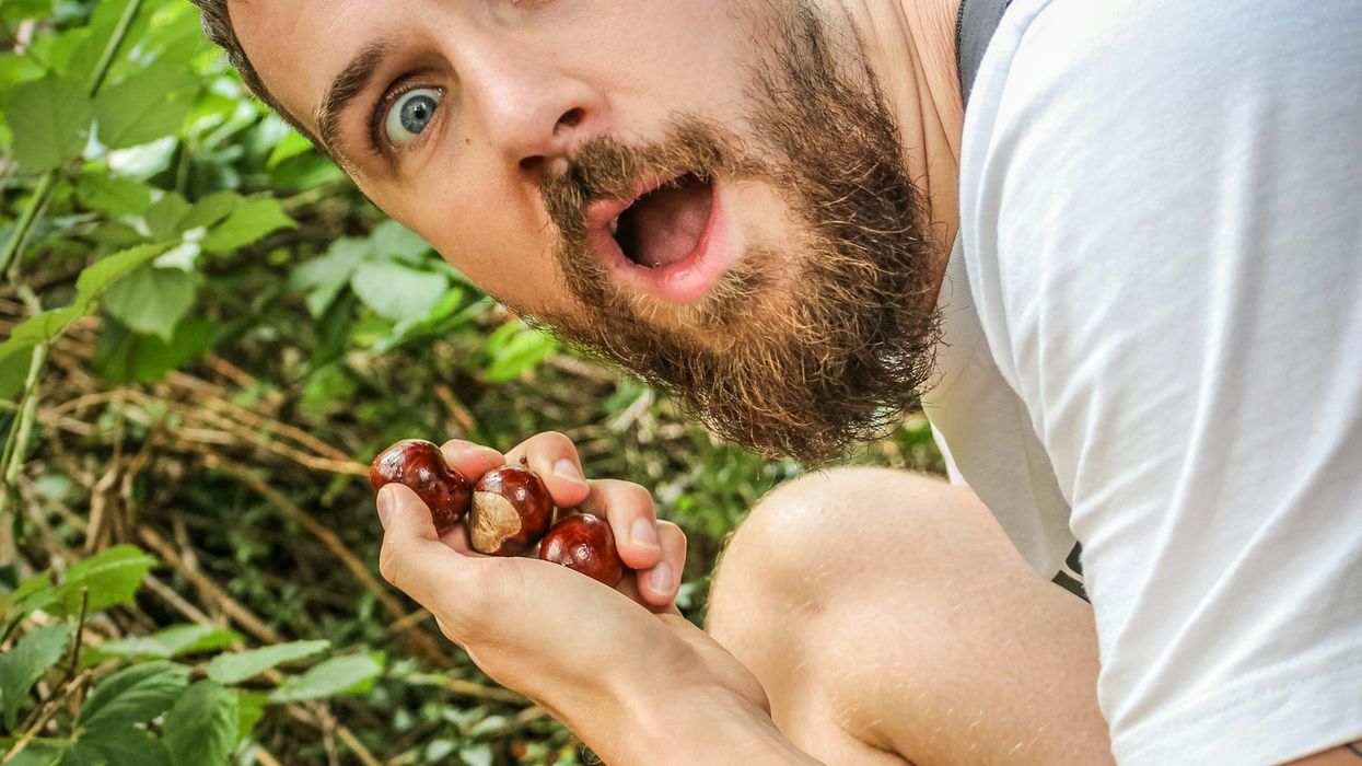 Close-up shot of an attractive, young man in a garden looking stunned.
