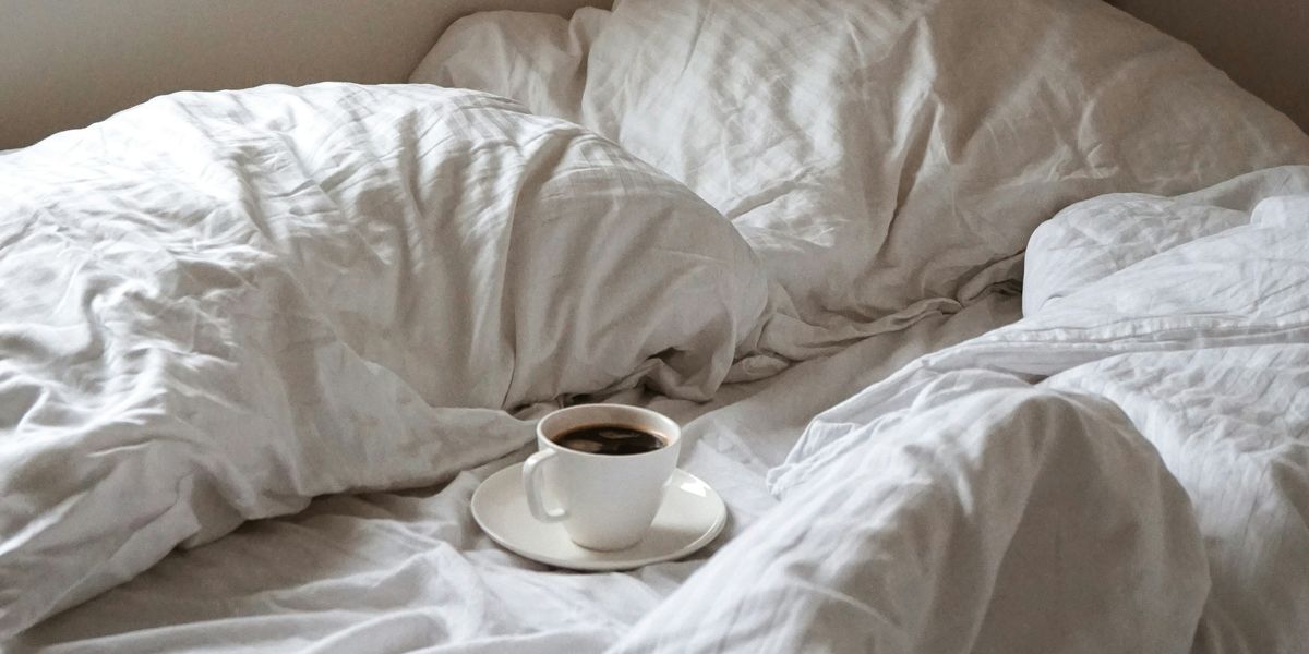 Cup of coffee on unmade bed