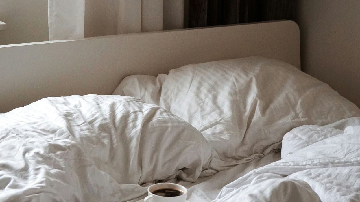 Cup of coffee on unmade bed