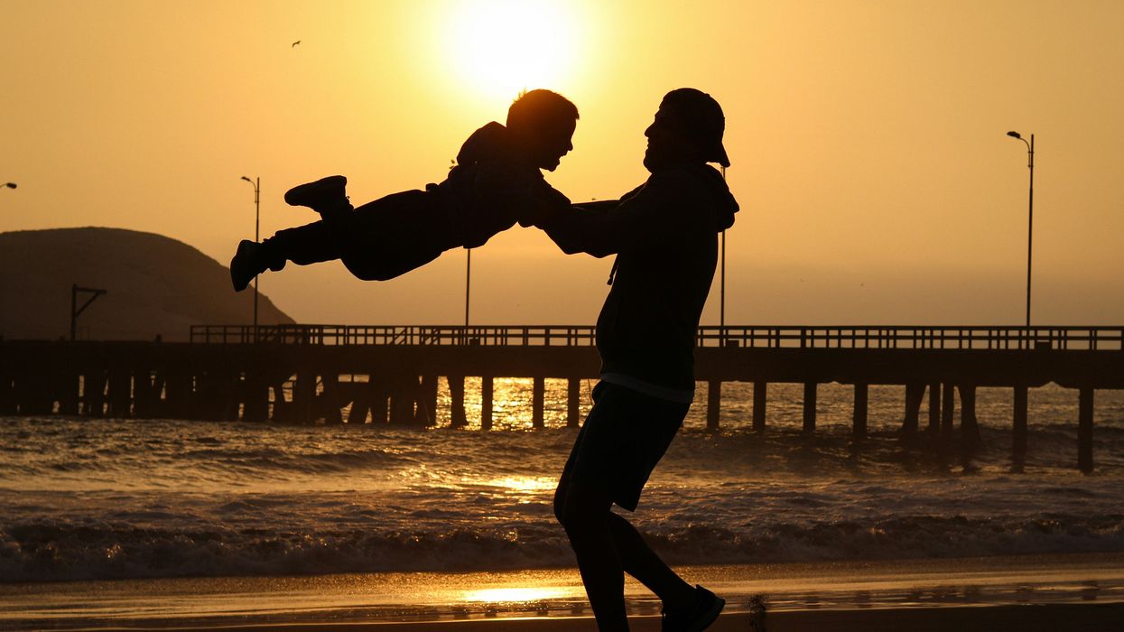 Dad playing with son on a sunset beach