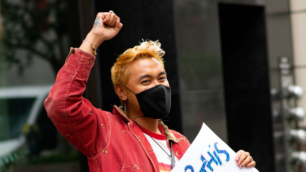 Demonstrator holds sign that reads, "Drop this act of corporate gree!"