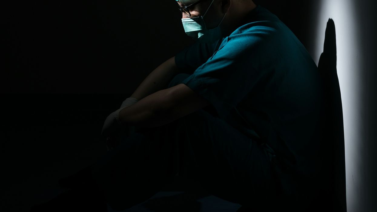 Despondent surgeon sitting on floor and leaned against wall