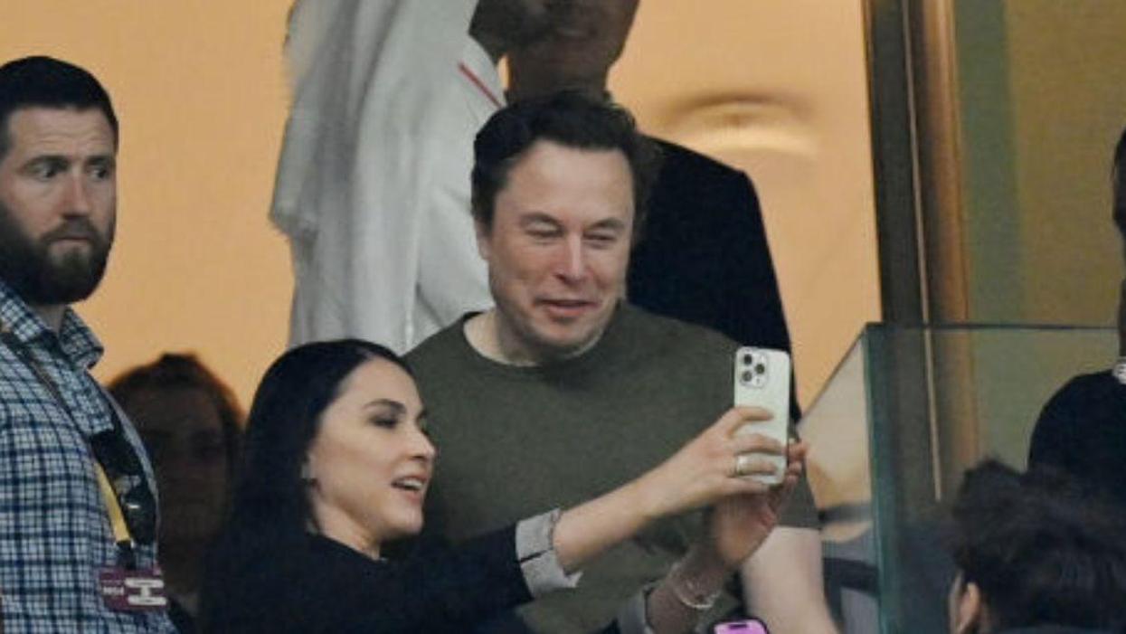 Elon Musk posing with a fan for a selfie at the FIFA World Cup 2022