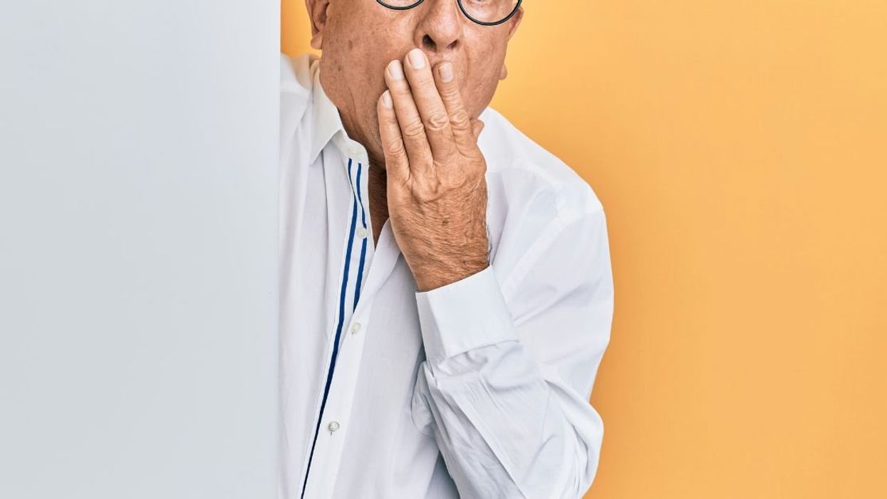 Embarrassed elderly man covering mouth with one hand