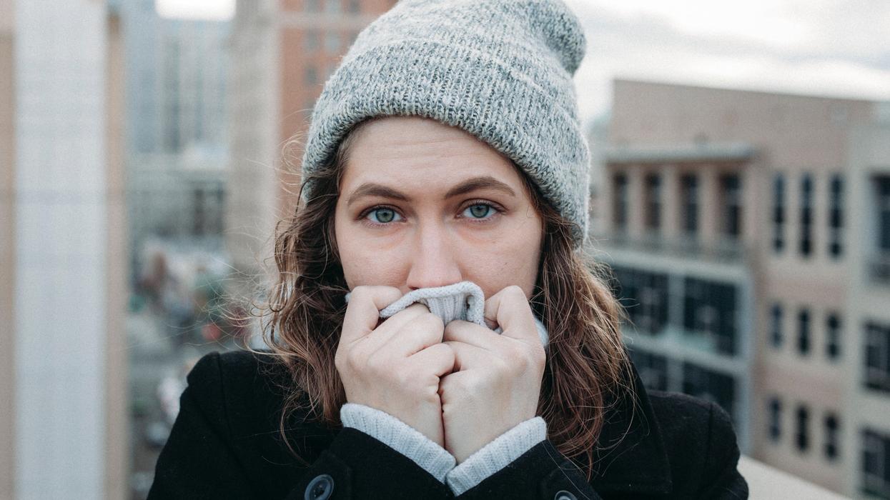 Embarrassed woman hiding her face behind her scarf