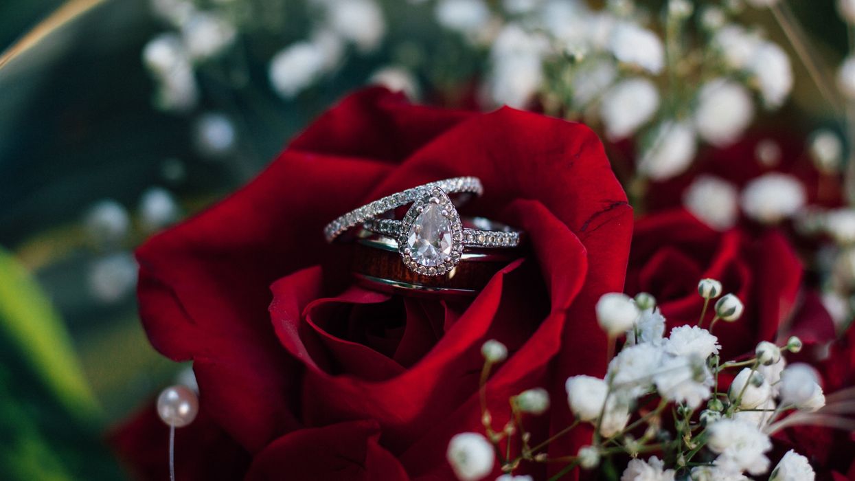 Engagement ring on top of red rose