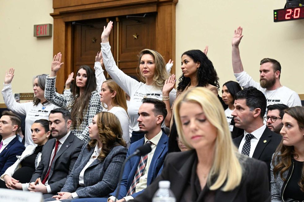 Epstein survivors raise their hands behind Pam Bondi during House Judiciary Committee hearing