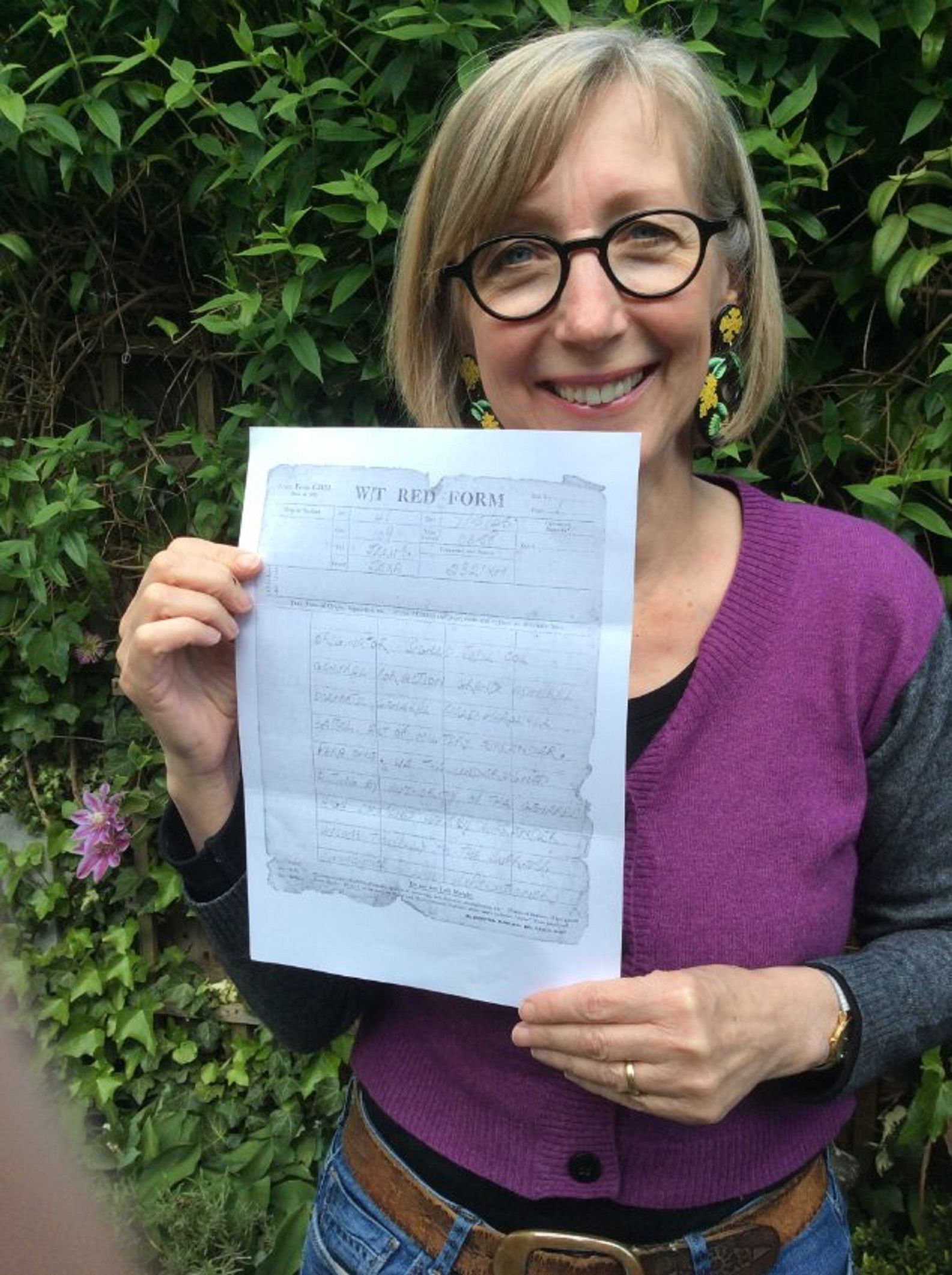 A picture of Dr Jennifer Iles with a copy of her father's note recording the German surrender from the end of the Second World War