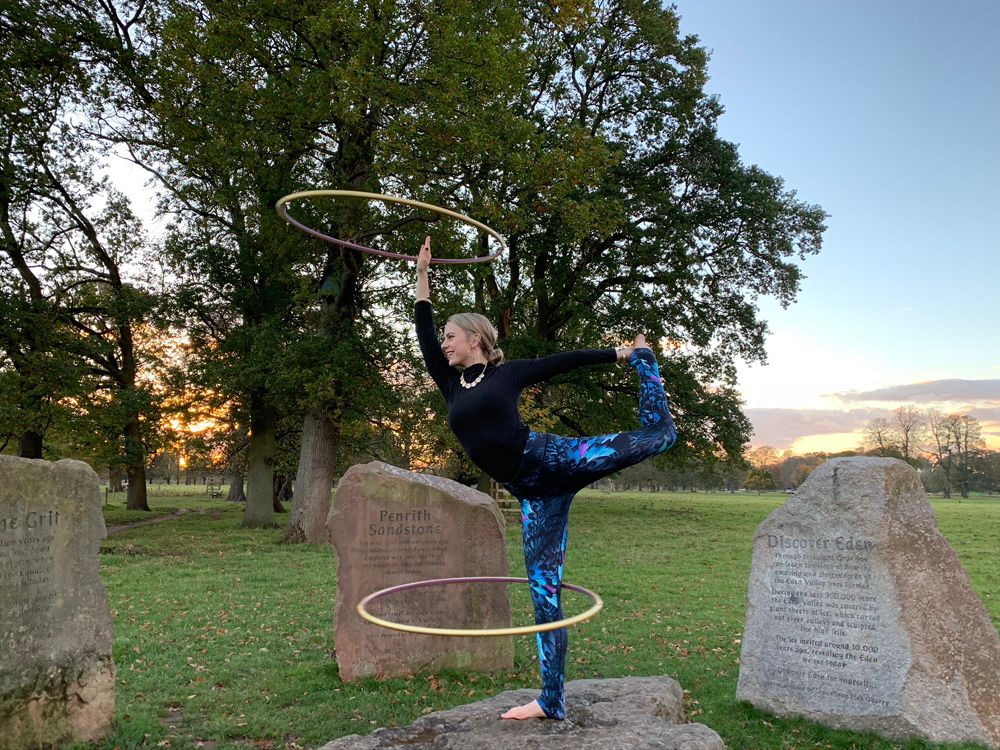 Woman dancing with wooden hoops outdoors