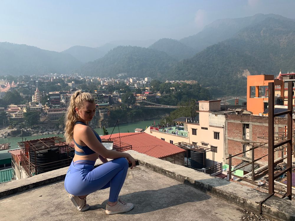 Woman crouching on rooftop with mountains in the background